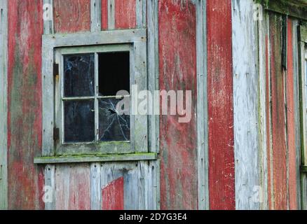 Old weathered red barn wall with a broken window. Stock Photo