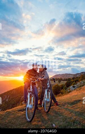 Active Senior Couple on country bike ride. Kissing on their break Stock Photo