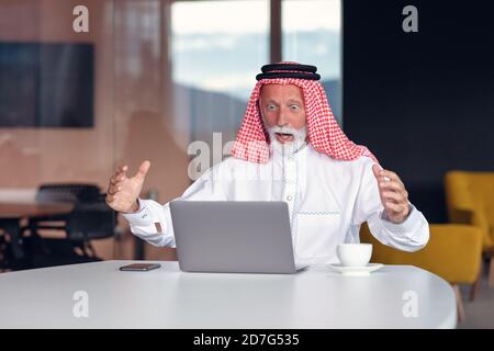 Arab businessman looks surprised while using a laptop Stock Photo