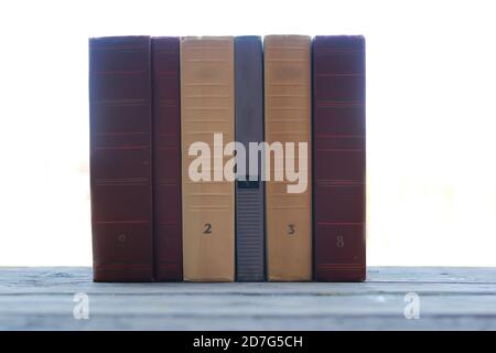 books standing different objects on a wooden table on a background of blurred summer foliage Stock Photo