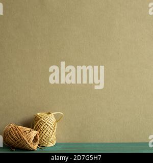 Brown string thread reel on wooden desk with khaki green background Stock Photo