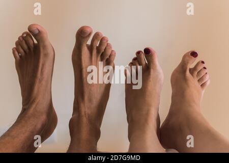 Close-up of a couple's feet in bed  against a white wall Stock Photo