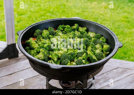 Vegetables and broccoli cooking in cauldron on fire outdoor. Stock Photo