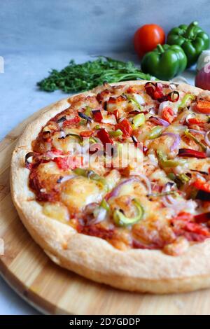 Food- Traditional Italian veggie pizza. Toppings are capsicum, corn, tomatoes, onion, red chilies, and cheese. Ingredients and vegetable background Stock Photo