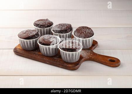 Many sweet tasty chocolate cupcakes on wooden cutting board Stock Photo