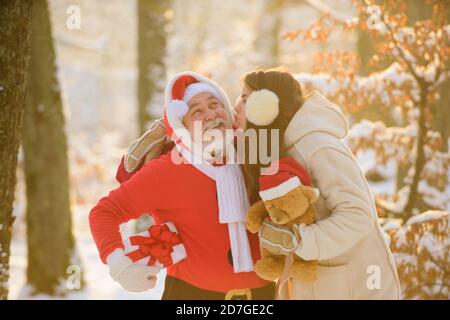 Santa Claus kisses a woman. Christmas and New year. Santa Claus with girl kissing outdoor in snow. Stock Photo