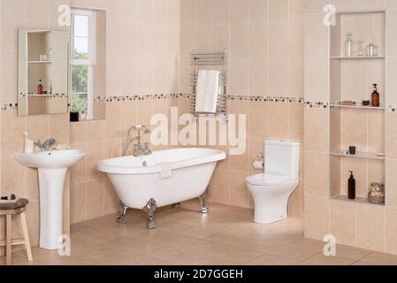 Elegant bathroom interior with luxury vintage bathtub, pedestal sink with a mirror, and toilet Stock Photo