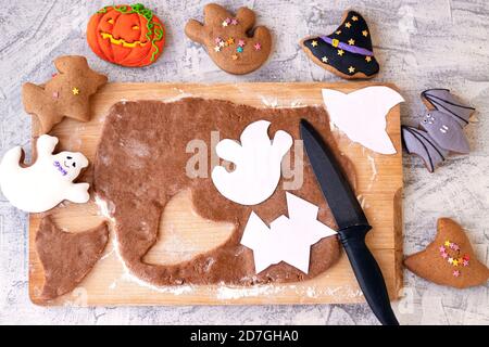 Halloween ginger cookies. Making homemade gingerbread cookies for Halloween. Halloween objects on textured table. Funny ginger biscuits. Top view. Toned. Soft focus. Stock Photo