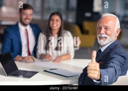 Young couple meeting financial advisor for home investment. Advisor showing thumbs up. Stock Photo