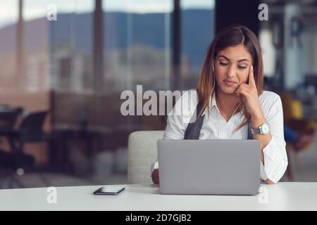 Portrait of focused woman in headphones taking part in webinar in office Stock Photo
