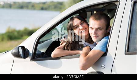 A young couple a girl and a man look out of the window of their car. Stock Photo