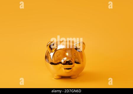 Golden piggy bank on yellow background. Golden money box. Money pig, money saving, moneybox, finance and investments concept. Free space for text Stock Photo