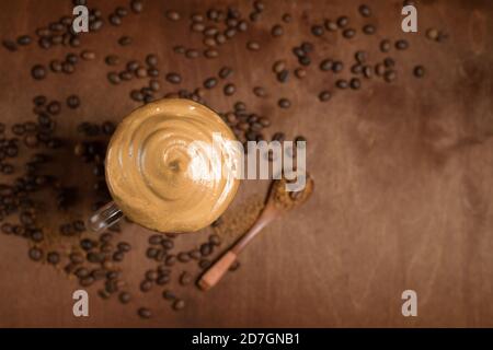 cold dalgona coffee in clear glasses on a dark wooden background. froth of sugar and instant coffee whipped with a mixer on top of cold milk. close up Stock Photo