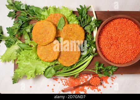 vegan lentil burgers in a wooden plate with green salad on a light background. vegetarian healthy food. lentils in a wooden plate. the view from the t Stock Photo