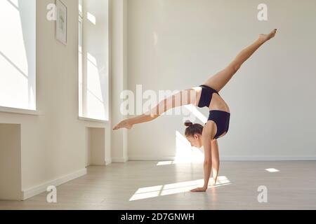 Girl gymnast practicing rhythmic gymnastics and body ballet in twine position on hands Stock Photo