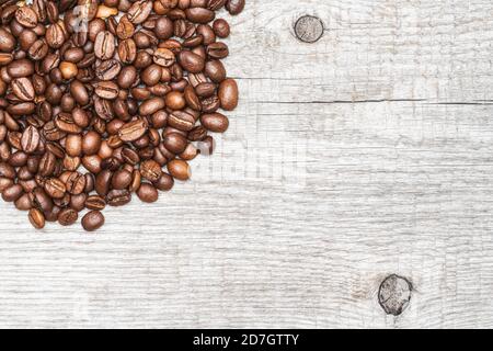 Brown coffee beans on light color wood background. Copy space. Close-up macro top view of still life. Stock Photo