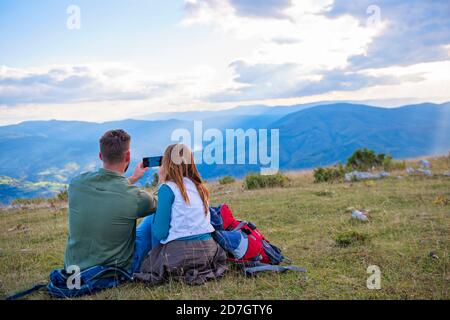 Couple Sitting On A Rock Resting During Hike Stock Photo