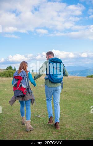 Happy couple hiking and enjoying a valley view. Photo taken from back. Stock Photo