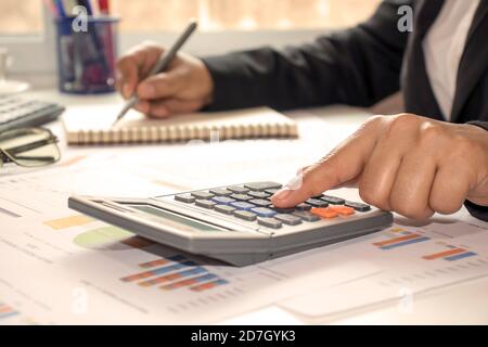 Close-up of businessmen or accountants holding a pen and pressing on the calculator to calculate business information, accounting documents, business Stock Photo