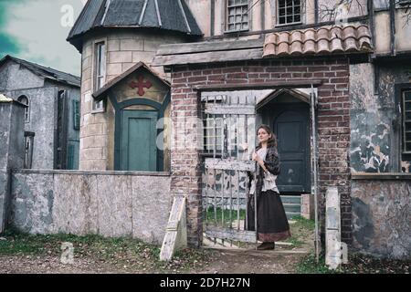 Portrait of a woman in ancient clothes at the gate to the courtyard of a retro Church in medieval Europe Stock Photo