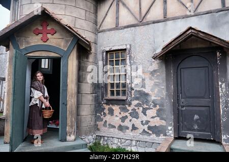 Parishioner in vintage clothes at the entrance to the retro Church with a large red cross over the door Stock Photo