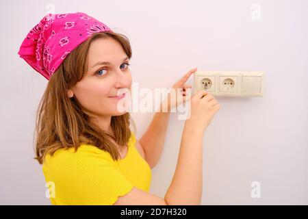 A woman twists a screwdriver into an electrical outlet. Repair electricians yourself Stock Photo