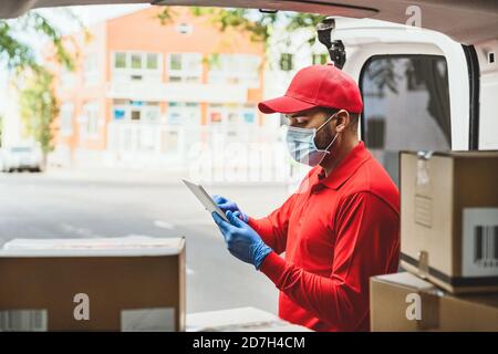 Delivery man wearing face protective mask to avoid corona virus spread - Young express courier working during coronavirus outbreak Stock Photo
