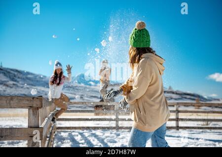 Happy adult girls are having fun and plays in snowballs at first snow in mountains Stock Photo