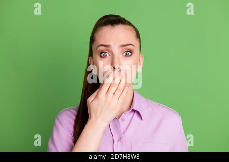 Photo of astonished frustrated girl share friends secret have fail close cover hand mouth lips wear violet lilac shirt isolated over green color Stock Photo