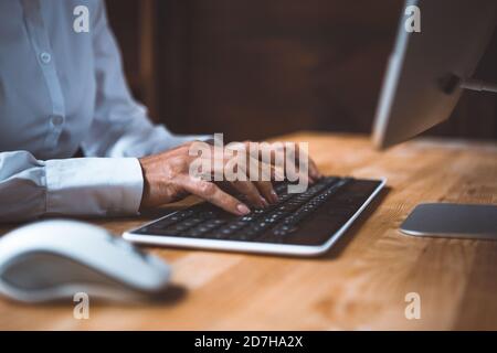 Businesswoman typing at computer keyboard. Close up shot of female hands. Toned image Stock Photo