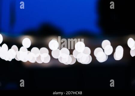 Blurred street light bulbs on black and blue evening city background Stock Photo