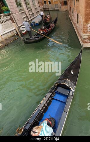 Gondoliers and tourists on the gondolas, typical Venetian rowing boat. Sightseeing tour along the Canals of the famous city. Veneto, Italy, Europe. Stock Photo