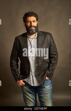 Young Indian man, in a blazer and denims, talking on his phone Stock Photo