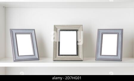 Three blank photo frames on a white shelf Stock Photo