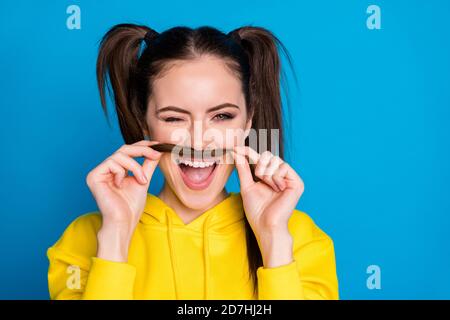 Closeup photo of charming pretty lady hold tail making fake mustache blinking eye like guy playful wear casual yellow hoodie pullover isolated bright Stock Photo