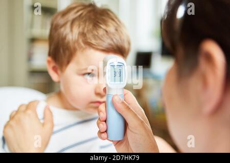 Pediatrician with infrared forehead thermometer when measuring a fever in a child Stock Photo