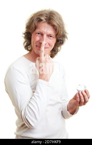 Laughing man puts cream on his face Stock Photo