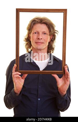 Man holds an empty wooden frame in front of his face Stock Photo