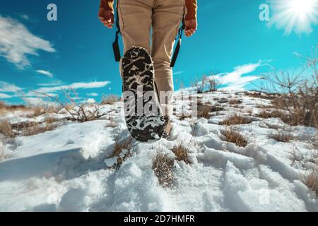 Lady hiker goes uphill by snowy surface. Closeup photo of woman legs Stock Photo