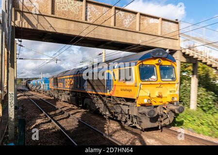 GB Railfreight Class 66 locomotive hauled leaf clearing freight train spraying the rails clean for improved traction. Autumn Rail Head Treatment Train Stock Photo