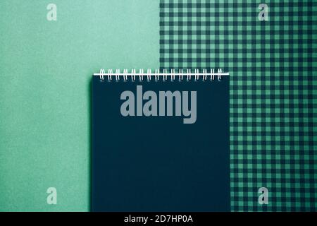 Open spiral notepad with black pages on a green checkered background. List of goals for the new year. Blank template Stock Photo