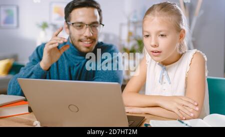 Bright Young Girl Studies with Kind Talented Teacher at Home, They Doing Homework. Foreign Language Teacher Tutors Smart Little Girl. They Use Laptop Stock Photo