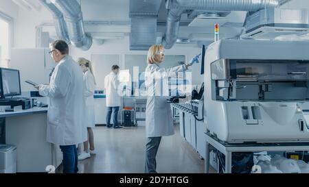 Team of Research Scientists Working On Computer, with Medical Equipment, Analyzing Blood and Genetic Material Samples with Special Machines in the Stock Photo