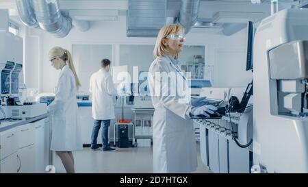 Team of Research Scientists Working On Computer, with Medical Equipment, Analyzing Blood and Genetic Material Samples with Special Machines in the Stock Photo