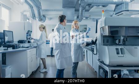 Team of Research Scientists Working On Computer, with Medical Equipment, Analyzing Blood and Genetic Material Samples with Special Machines in the Stock Photo