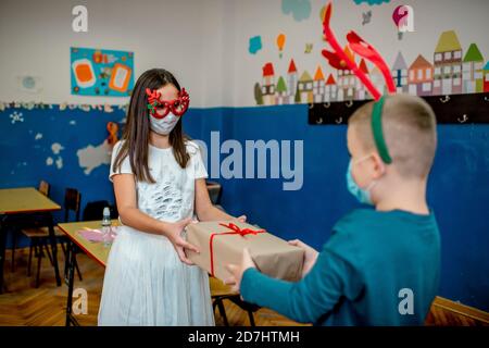 School children celebrating New Year in the classroom. They are wearing protective face mask Stock Photo