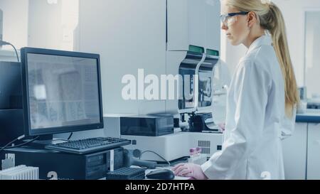 Female Research Scientist Working with Medical Analyzing Machine for Testing Tubes with Blood Sample. Scientist Works in Innovative Pharmaceutical Stock Photo