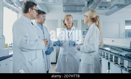 Team of Research Scientists Have Meeting, They Have Discussion While Standing in the Middle of Laboratory. People in Innovative Modern Lab Doing Stock Photo