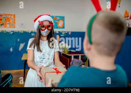 School children celebrating New Year in the classroom. They are wearing protective face mask Stock Photo