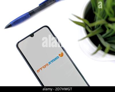 Lod, Israel - July 8, 2020: Modern minimalist office workspace with black mobile smartphone with Meuhedet Health Services app launch screen with logo Stock Photo